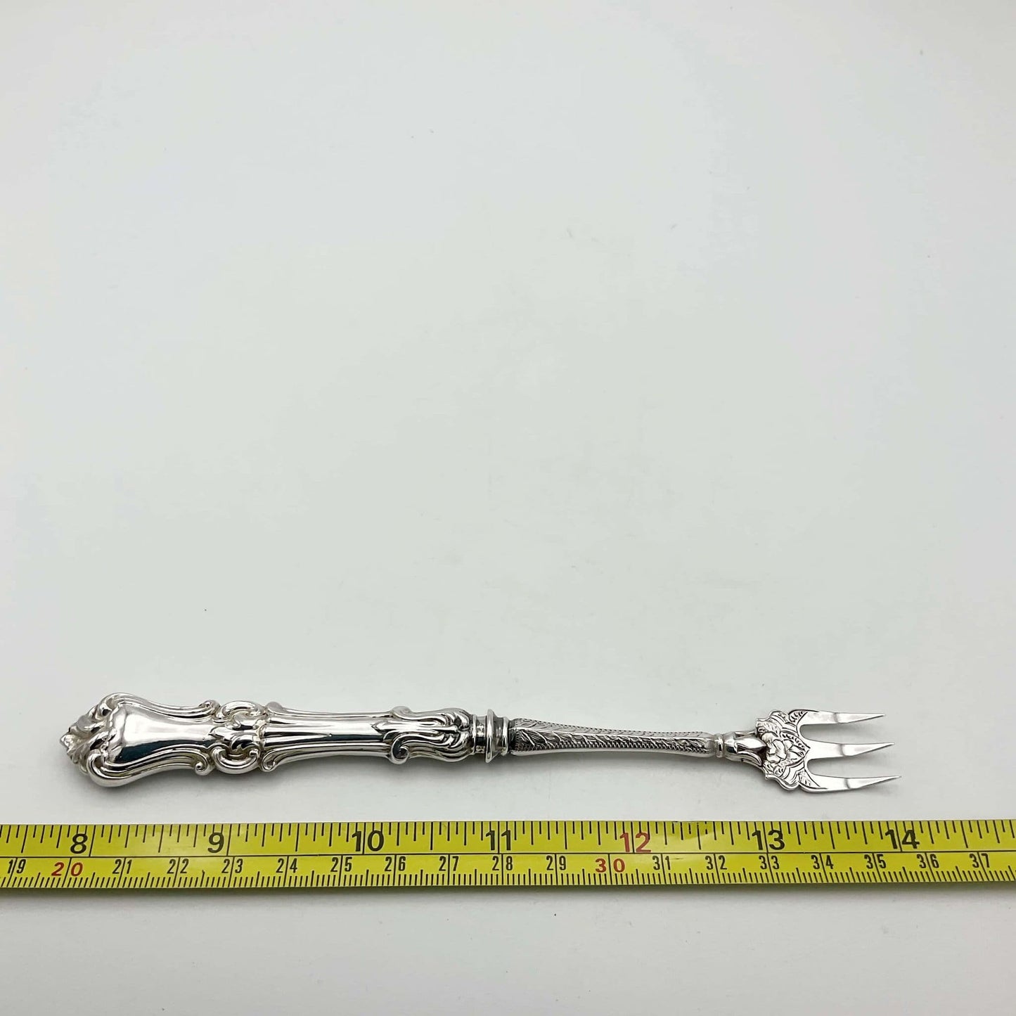 Antique Pickle fork next to tape measure showing it to be 16.5cm in length