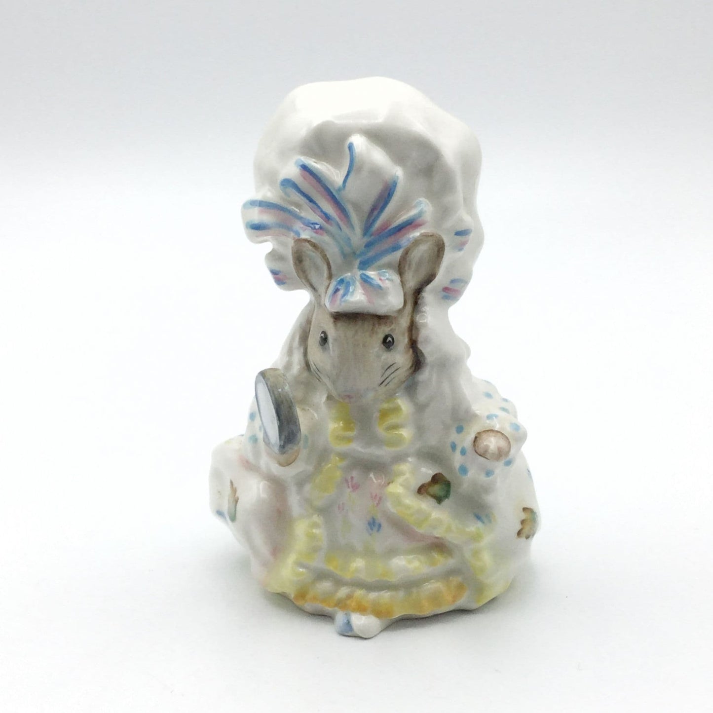 A ceramic figurine of Lady Mouse from Beatrix Potter stories, wearing a mob cap and looking into a hand mirror.