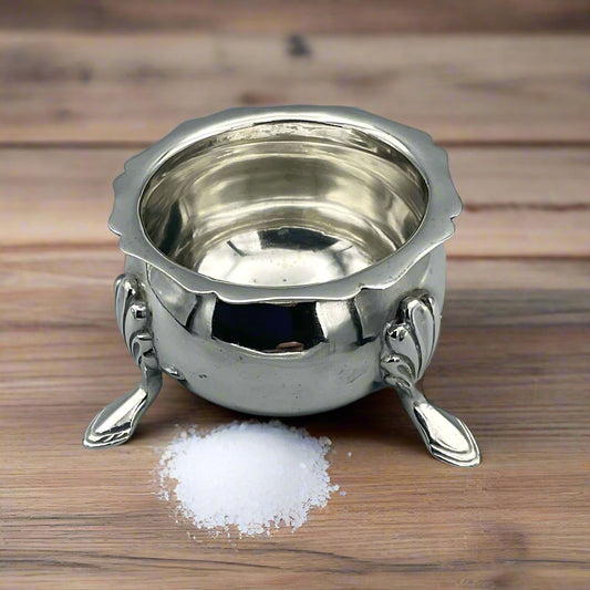 Silver salt on a wood table with a pile of salt next to it