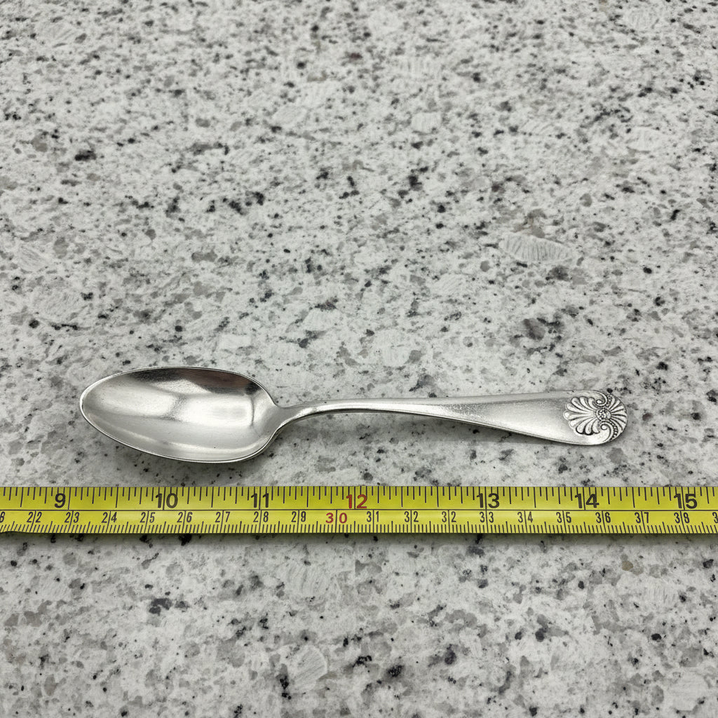 silver spoon next to a tape measure on a dark granite surface