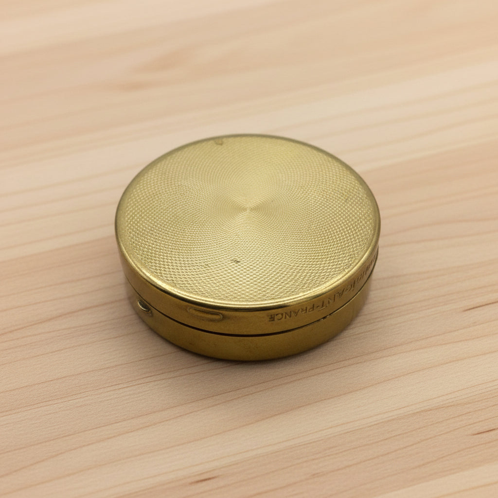 base of Houbigant brass compact showing a beautiful pattern on a wood table