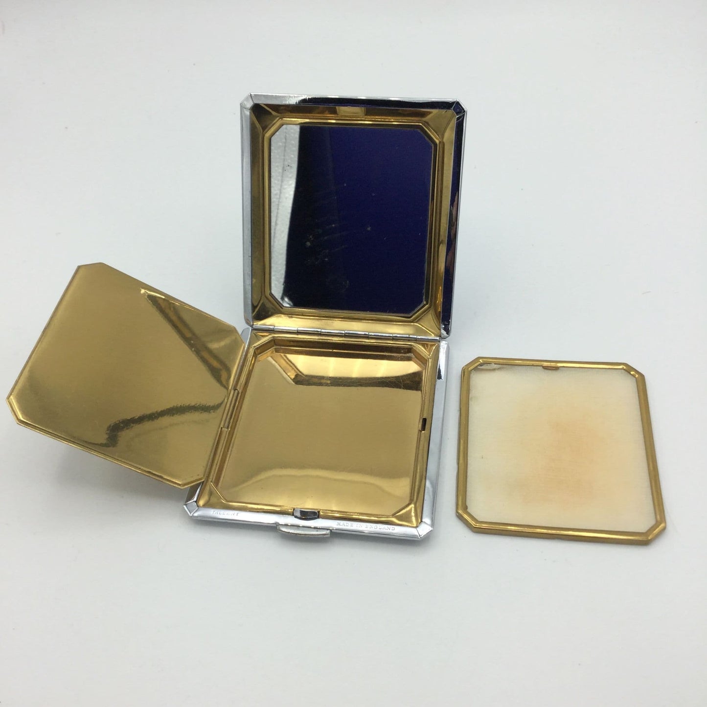 inside the powder compact showing the mirror, inner lid, golden interior and powder screen