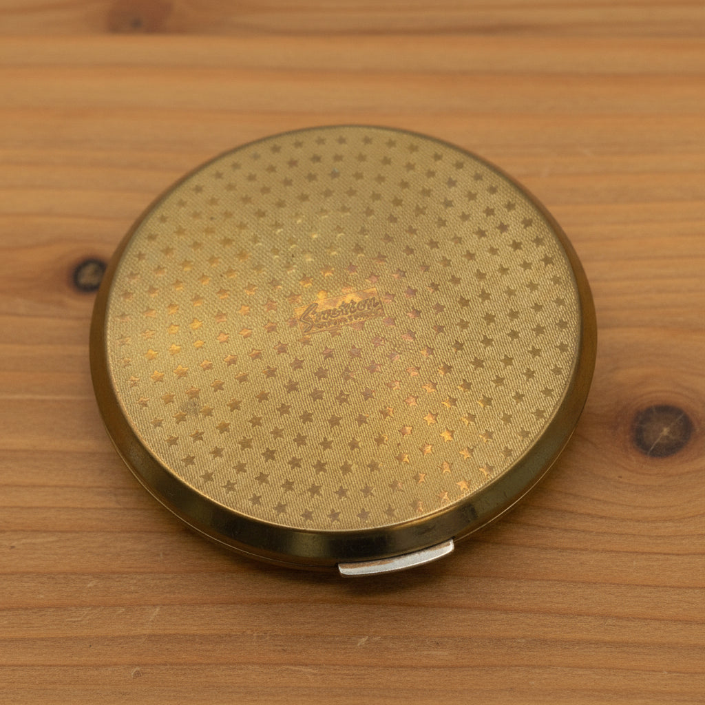 1960s gold mirror compact base showing a stars design with Stratton in the centre on wood