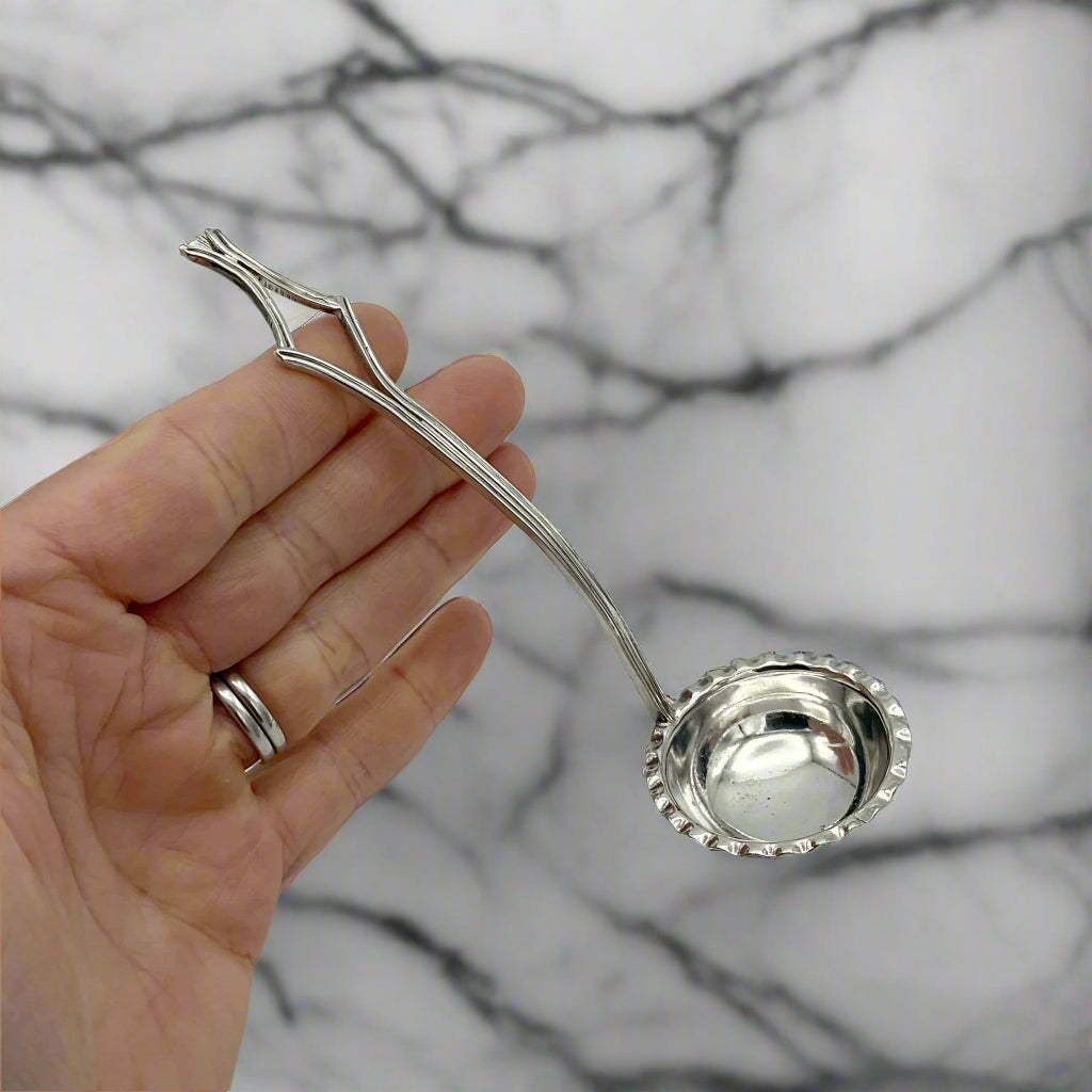 small ladle resting on a hand on a marble surface