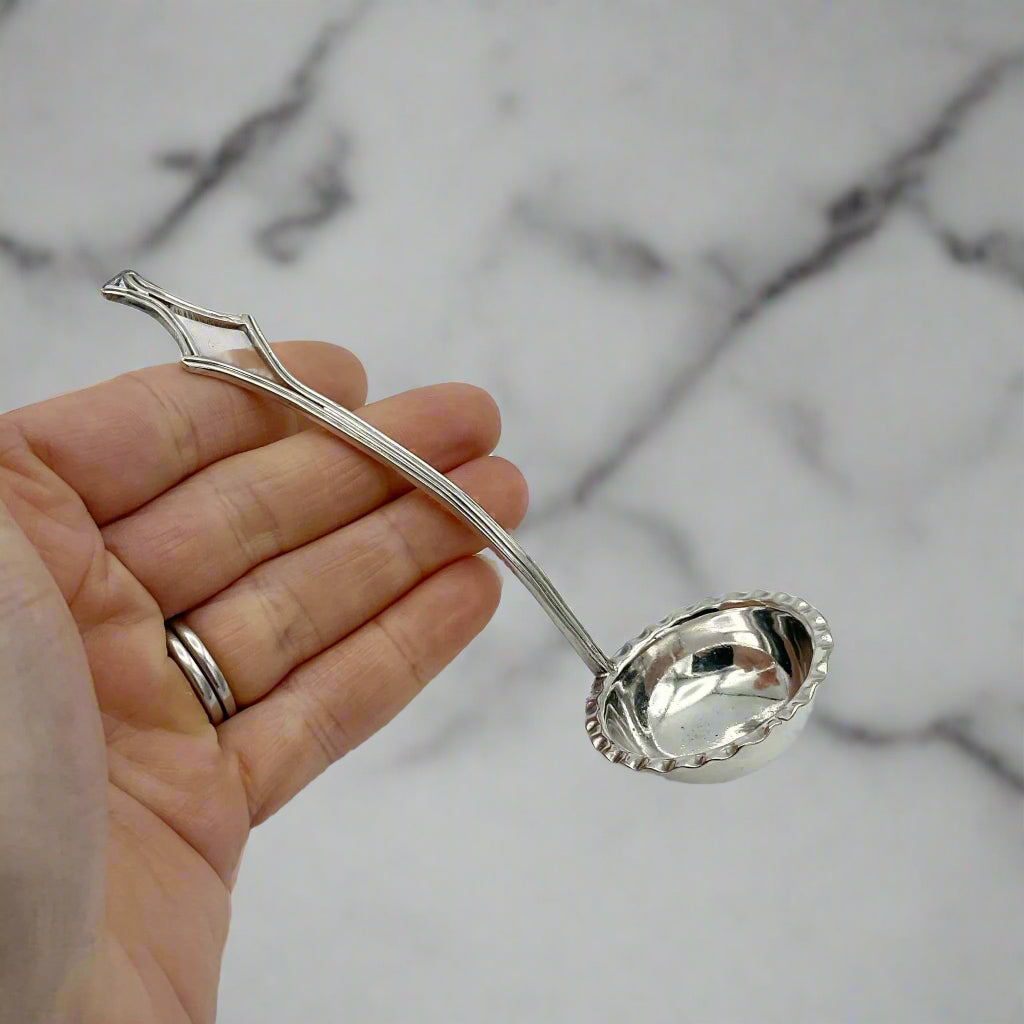 small ladle hel in a hand with a marble background