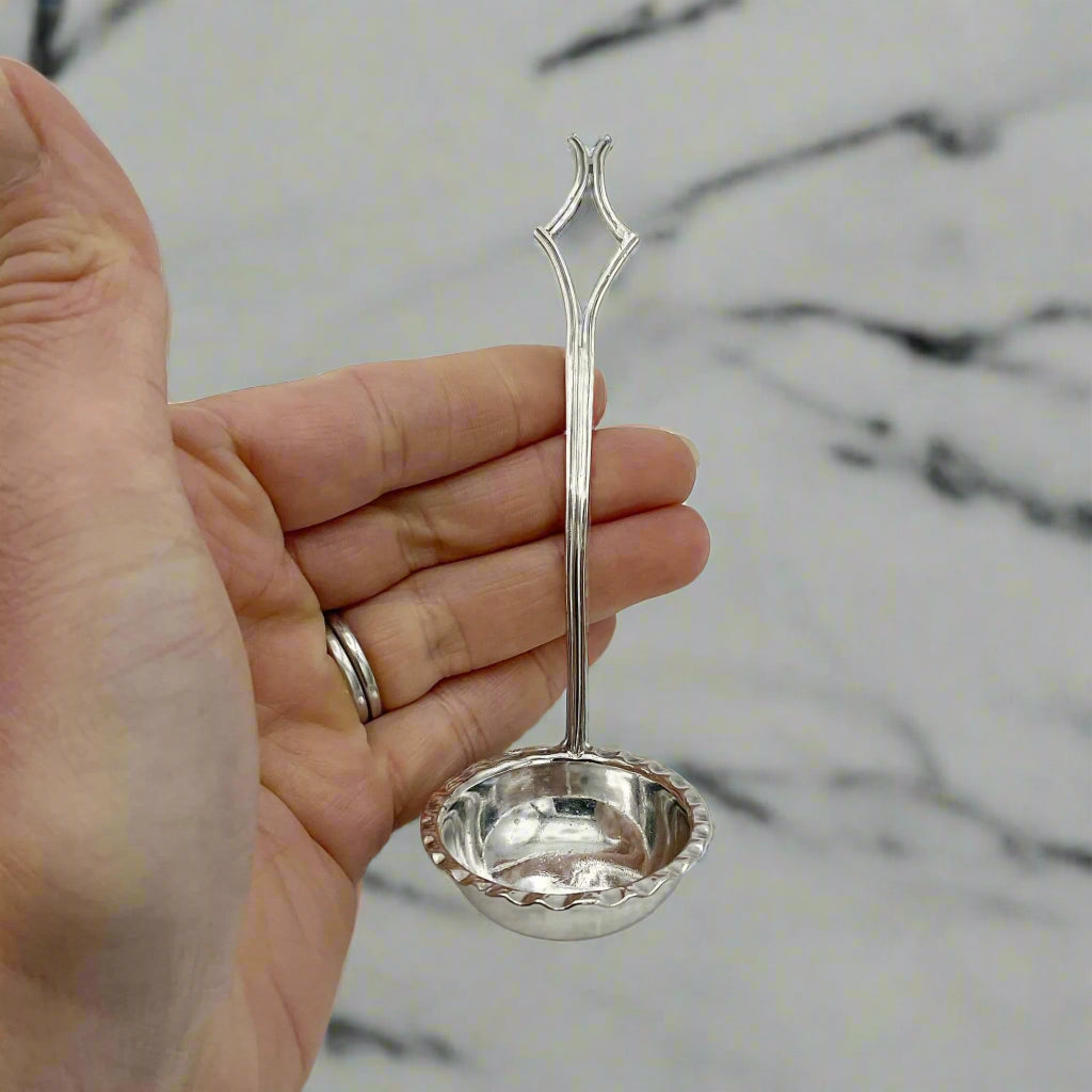 small ladle held in a hand on a marble background
