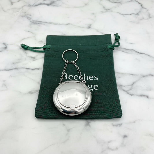 Antique sterling silver chatelaine case with a chain handle, displayed in a green gift bag on marble worktop