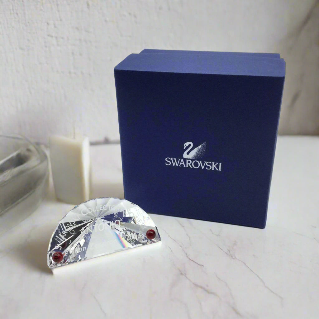A Swarovski crystal plaque with two deep red spots, presented in its original navy blue Swarovski presentation box.