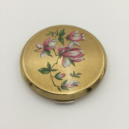 Brushed gold powder compact featuring pink and white flowers on the lid