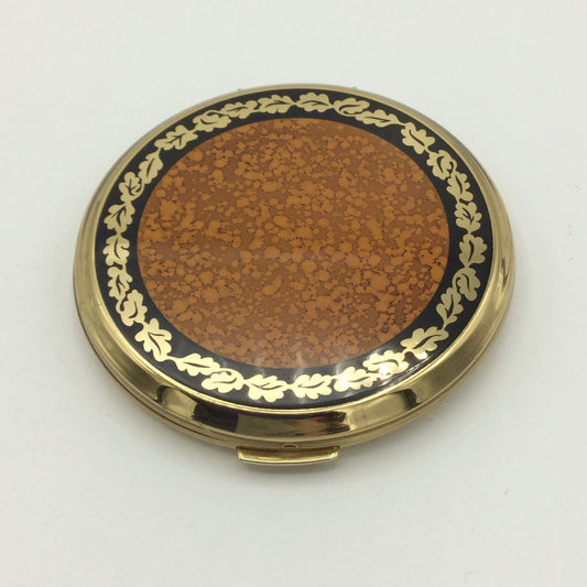 A Stratton mirror compact with an orange and brown enamel with a gold and black edge