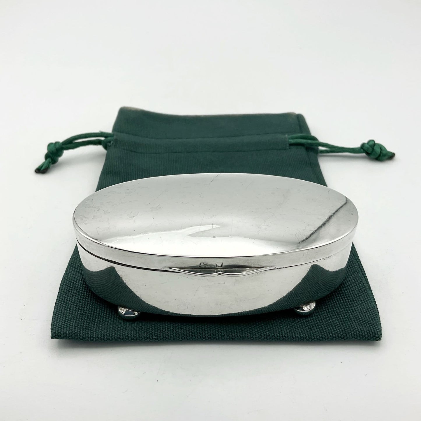 Shiny silver jewellery box sitting on a green cotton bag