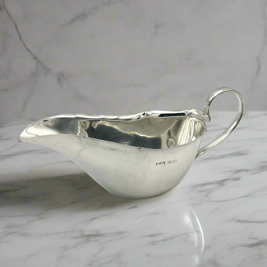 Silver gravy boat with hallmarks on marble background 