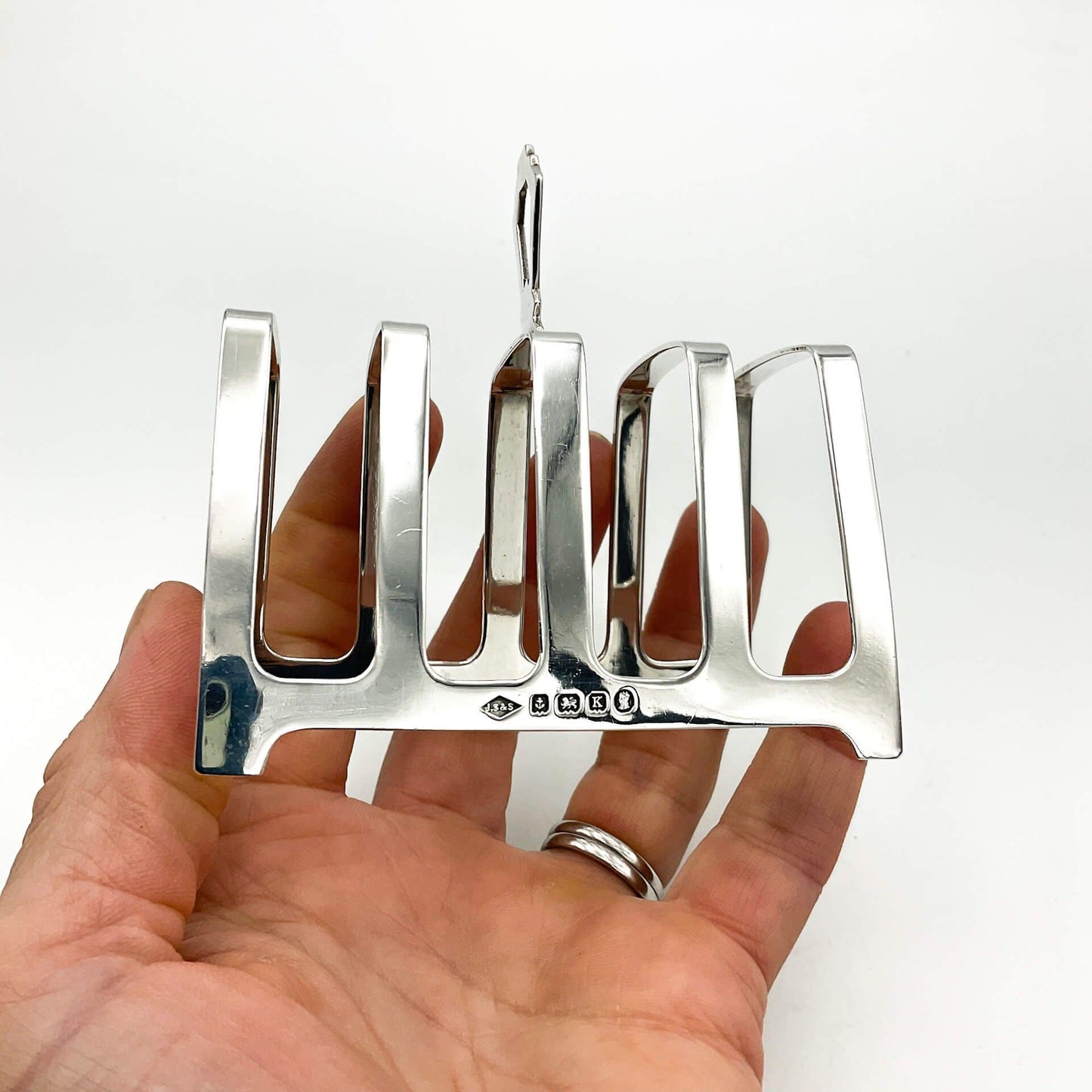 Art deco style silver toast rack on a white background Held in hand