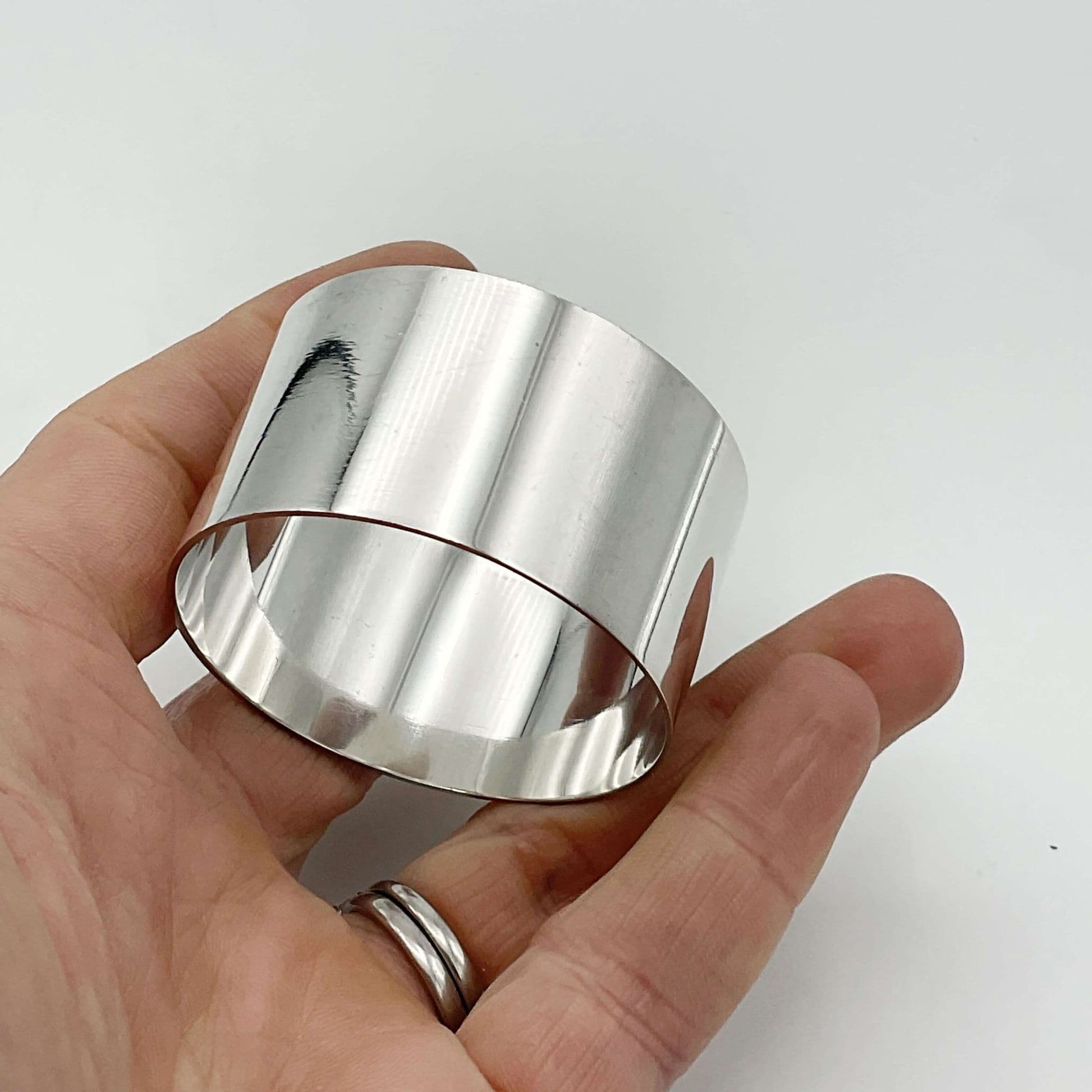 A lovely shiny silver napkin ring held in a hand