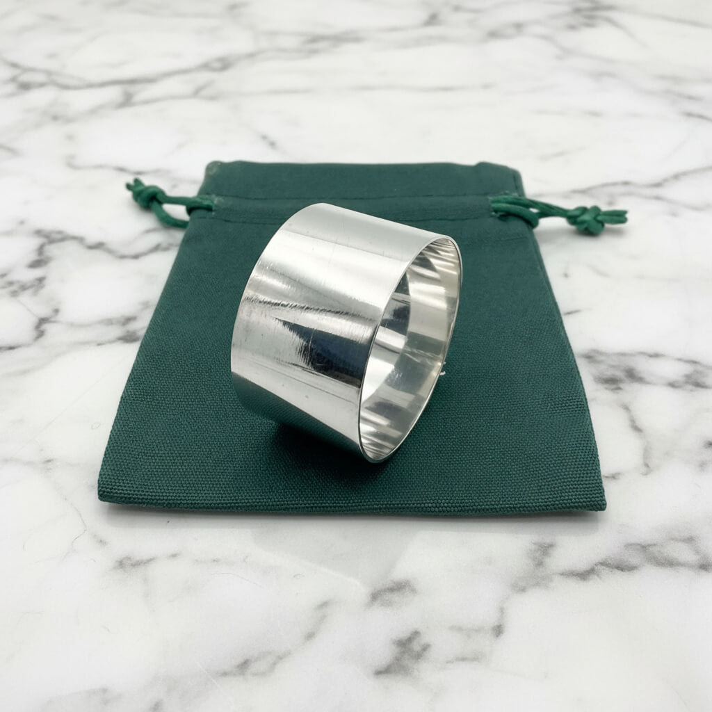 The silver napkin ring sitting on a green gift bag.