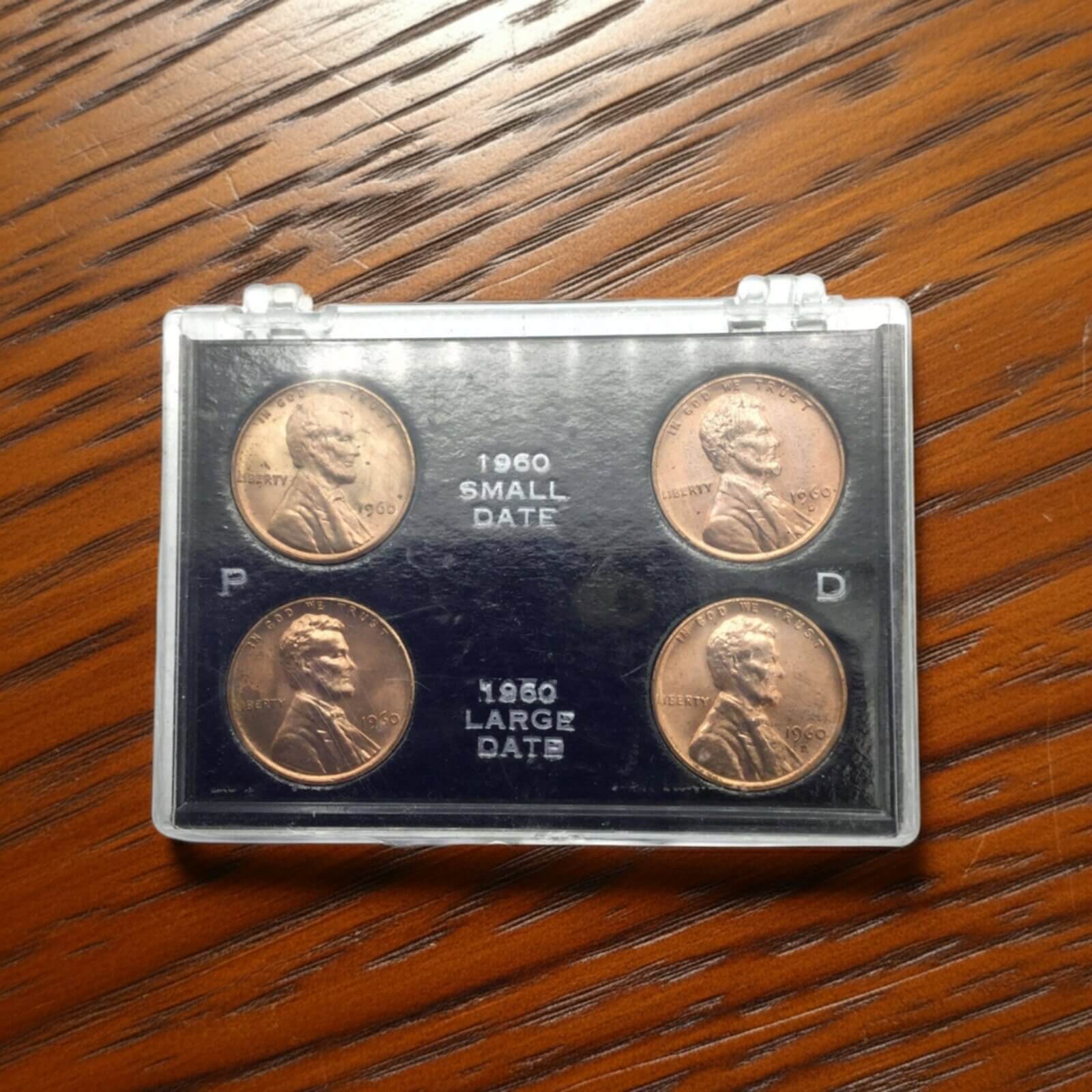 Set of four coins in a display case on a wooden surface