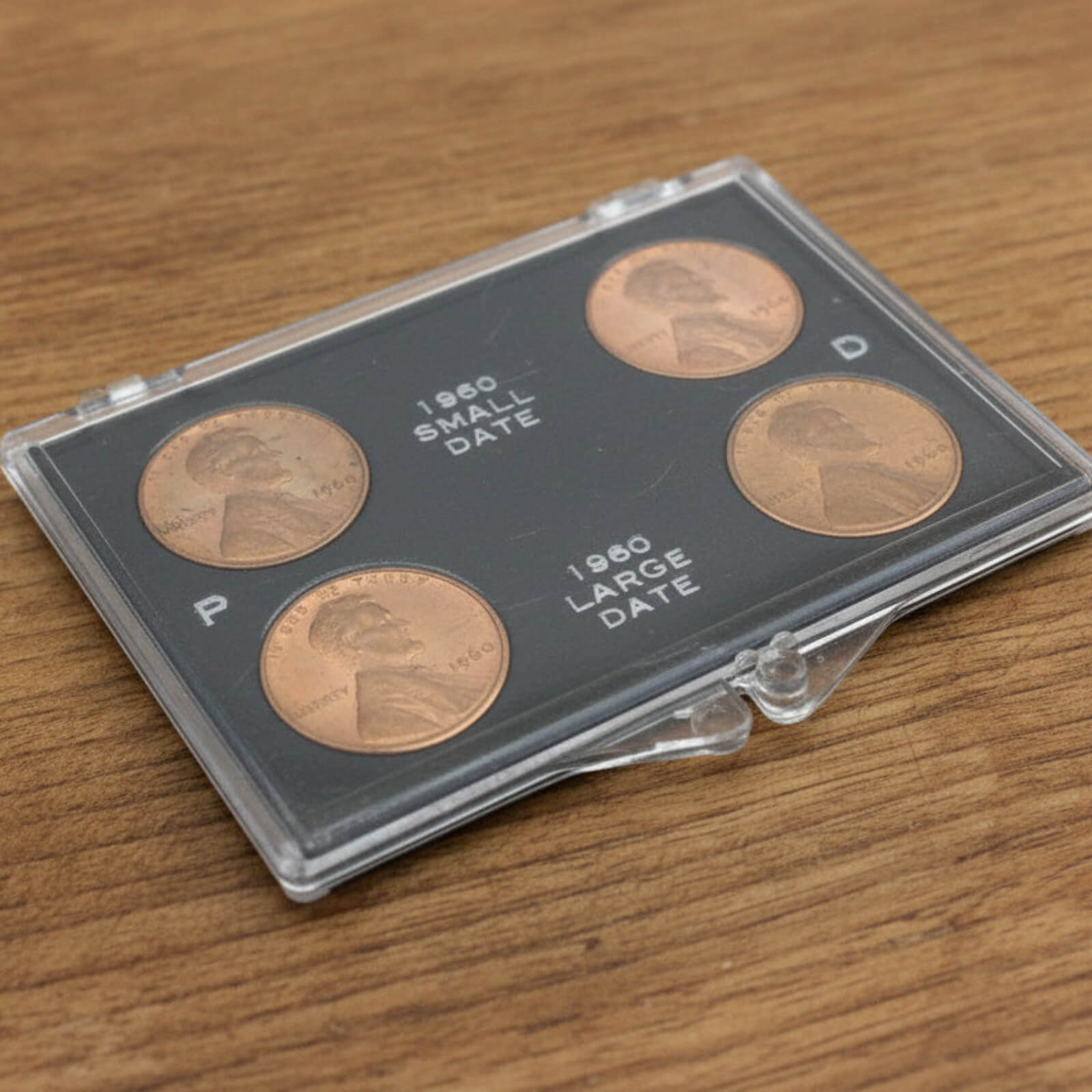 Set of four coins in a clear holder on a wooden surface