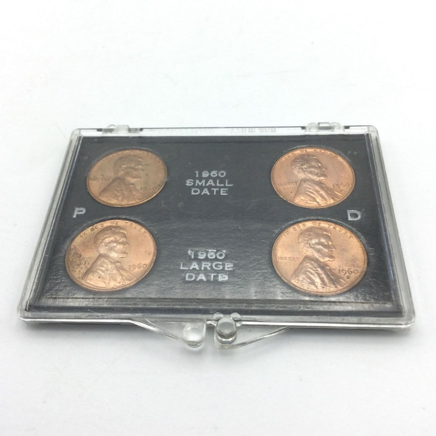 Set of four pennies in a display case on a white background