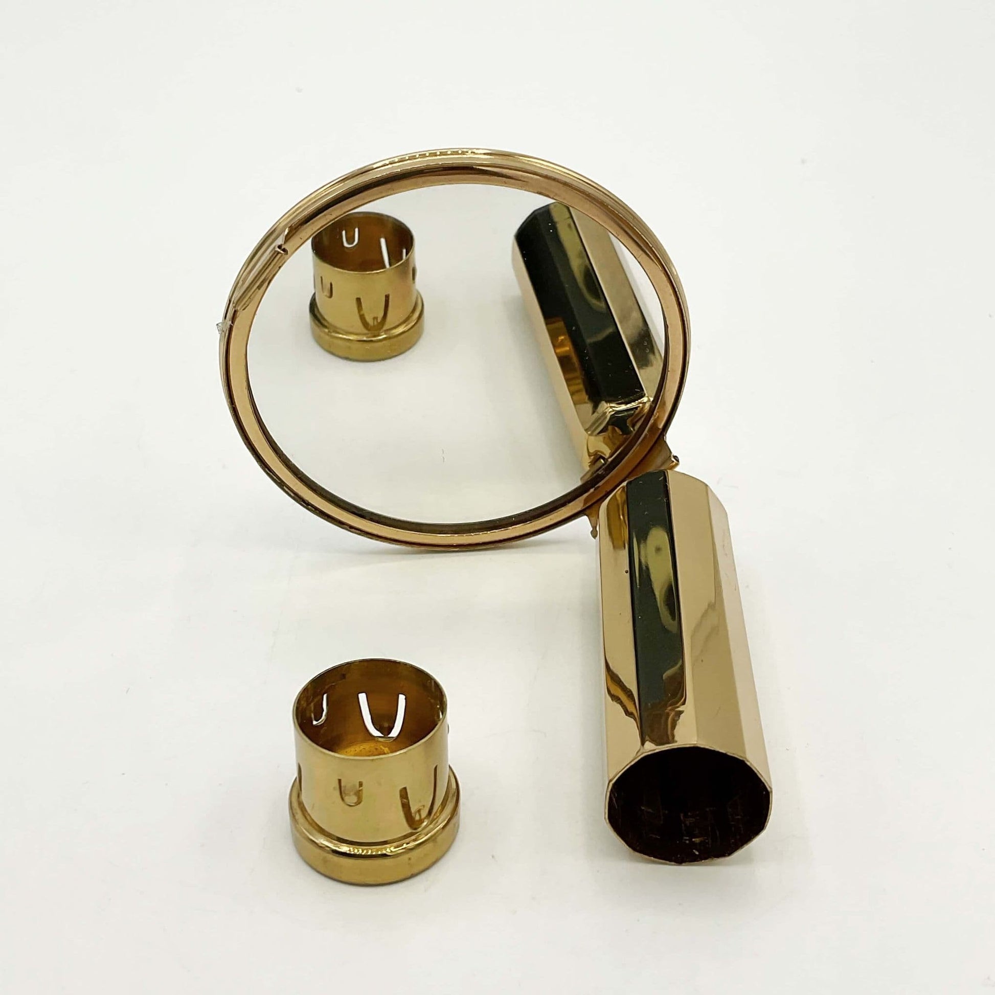 A gold coloured lipstick case with a mirror attached to the end. The mirror is showing a clear reflection and the end of the lipstick holder shows it is ready for a lipstick