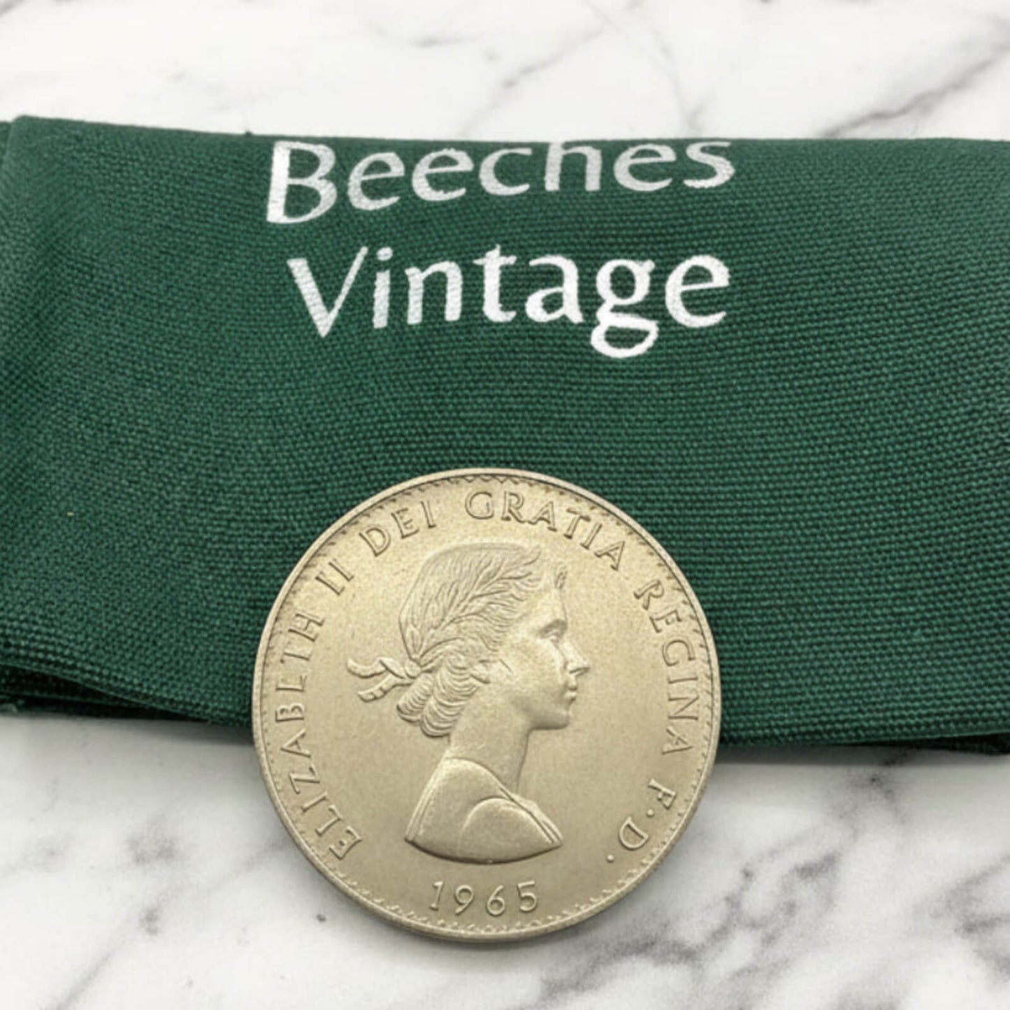 Vintage coin with 'Beeches Vintage' label on a marble surface