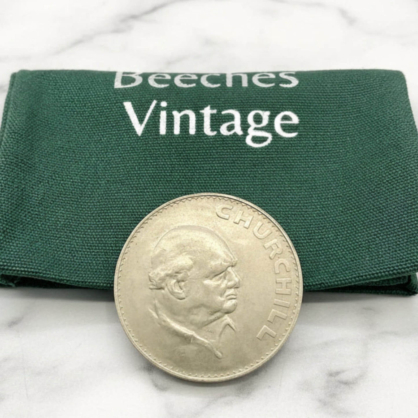 Silver coin with a portrait on a green 'Beeches Vintage' cloth background