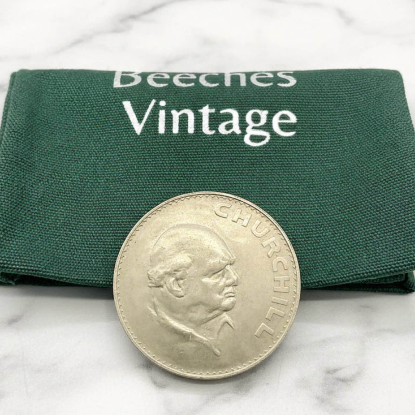 Silver coin with a portrait on a green 'Beeches Vintage' cloth background