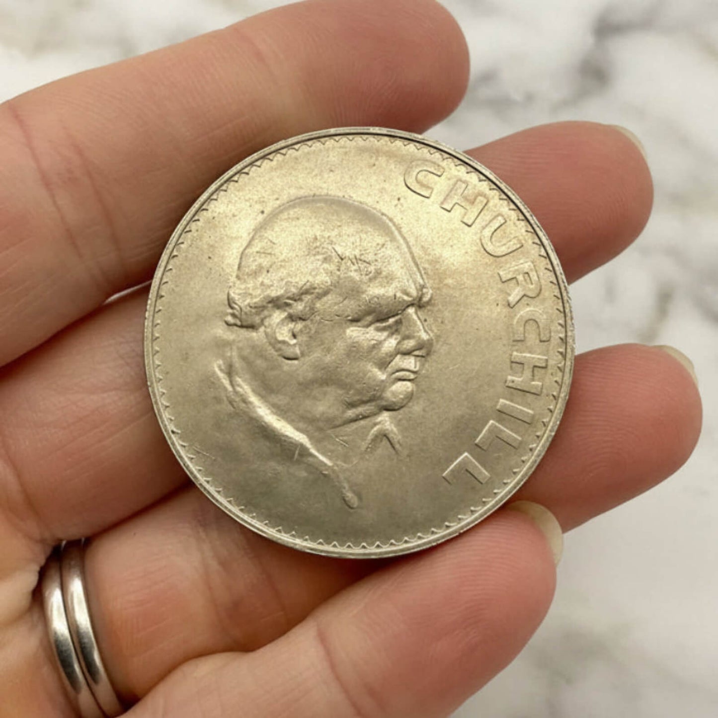 Silver coin with a portrait on a hand against a blurred background