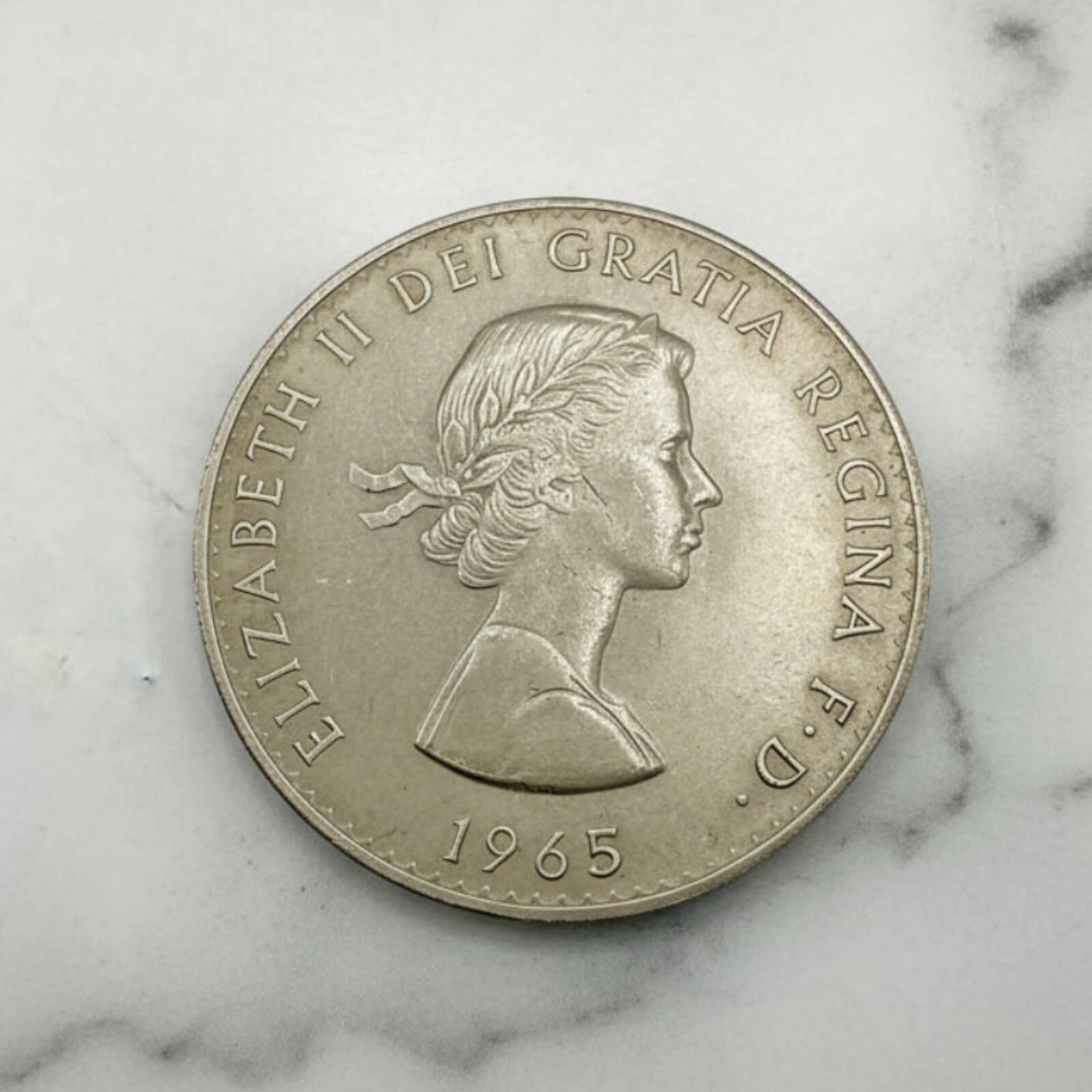 Silver coin with a profile of a queen on a marble surface