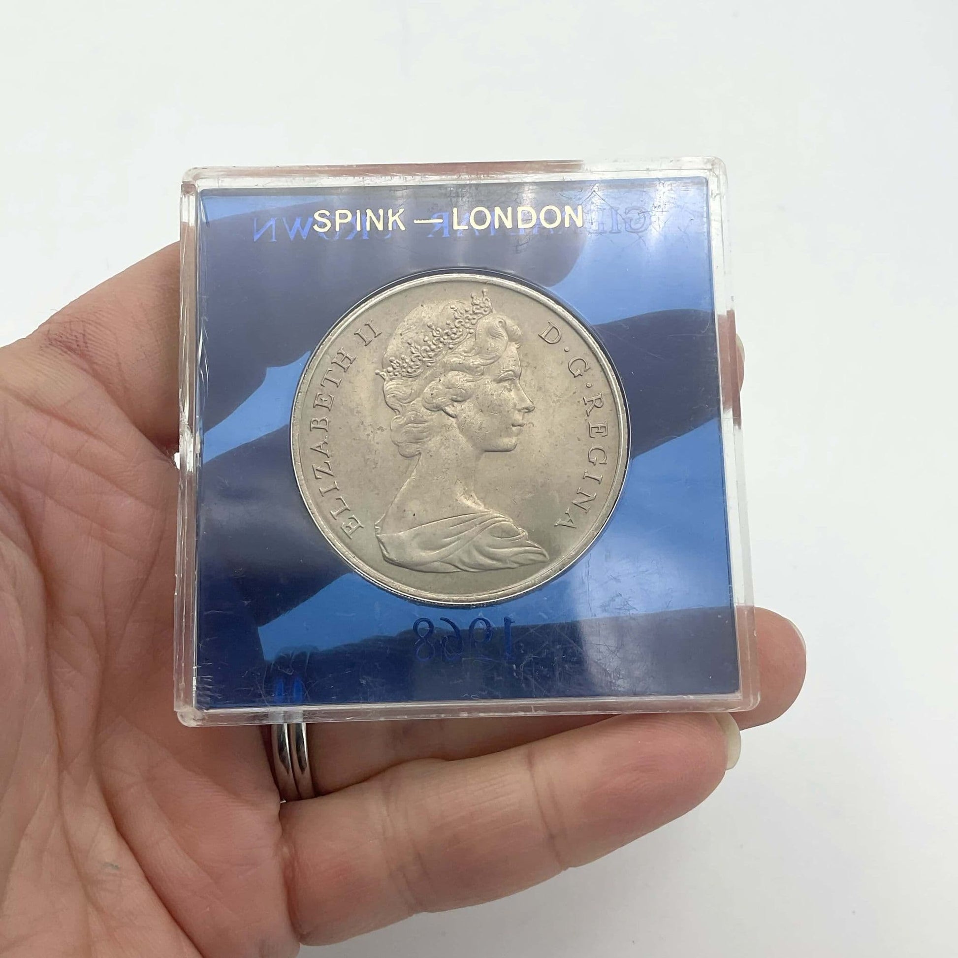 Silver Gibraltar Crown coin in a blue case held in a hand