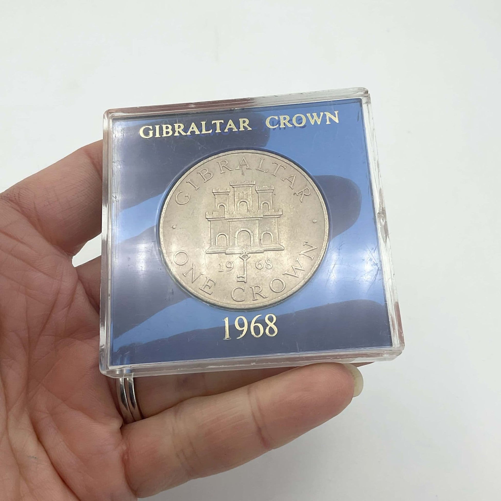 Silver Gibraltar Crown coin in a blue case held in a hand