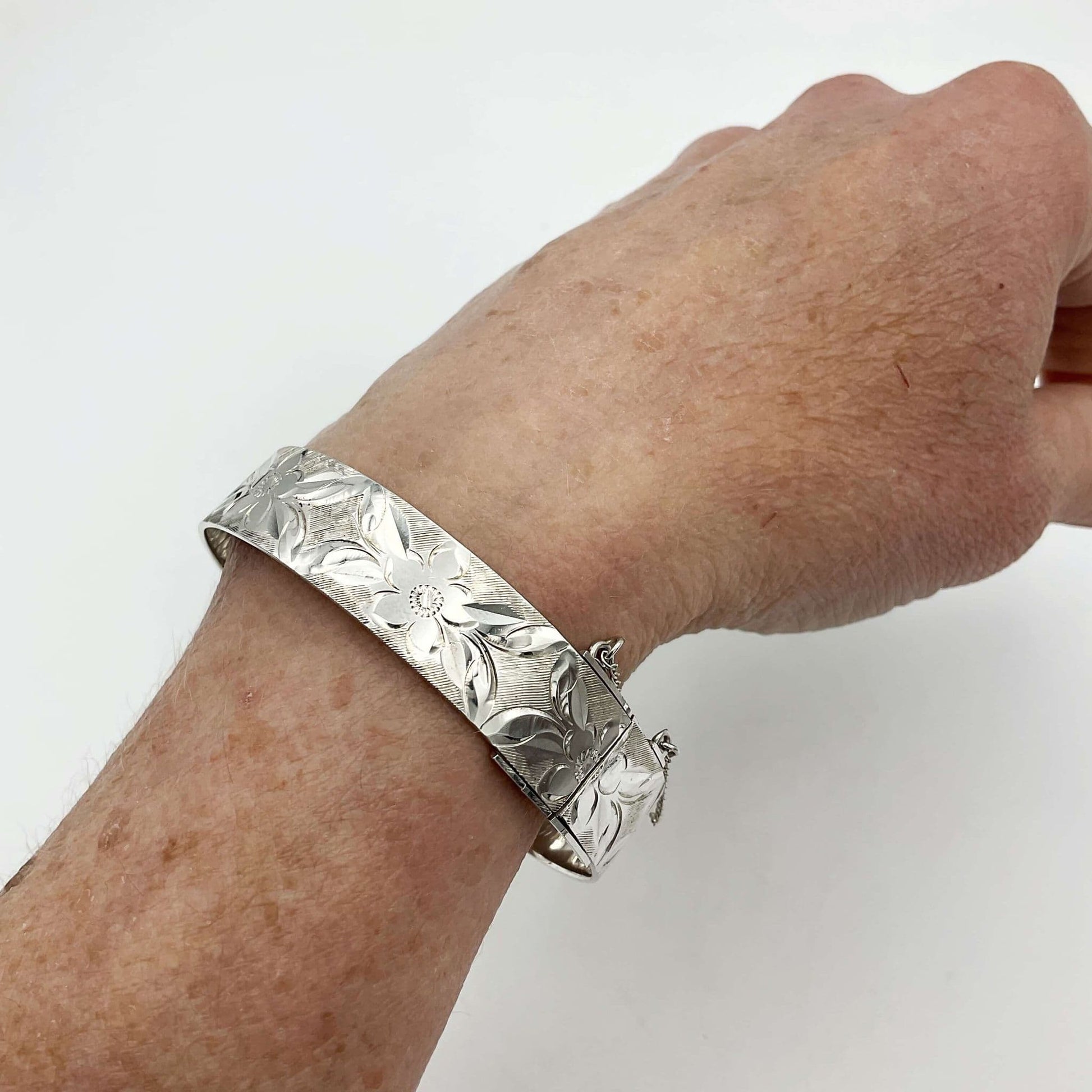 Silver bracelet with engraved flowers on a wrist