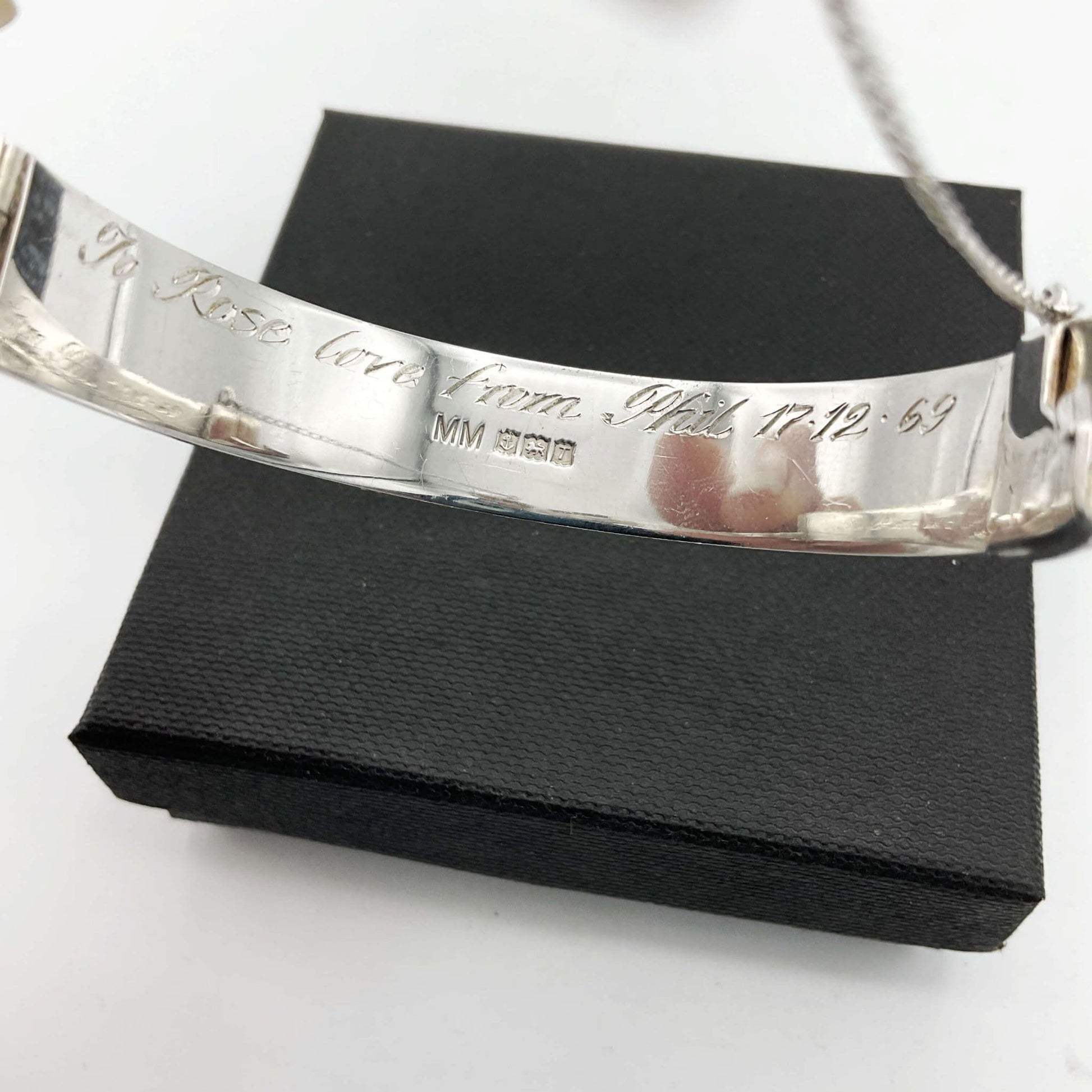 Inside of silver hinged bracelet showing the maker's mark, hallmarks and engraved message