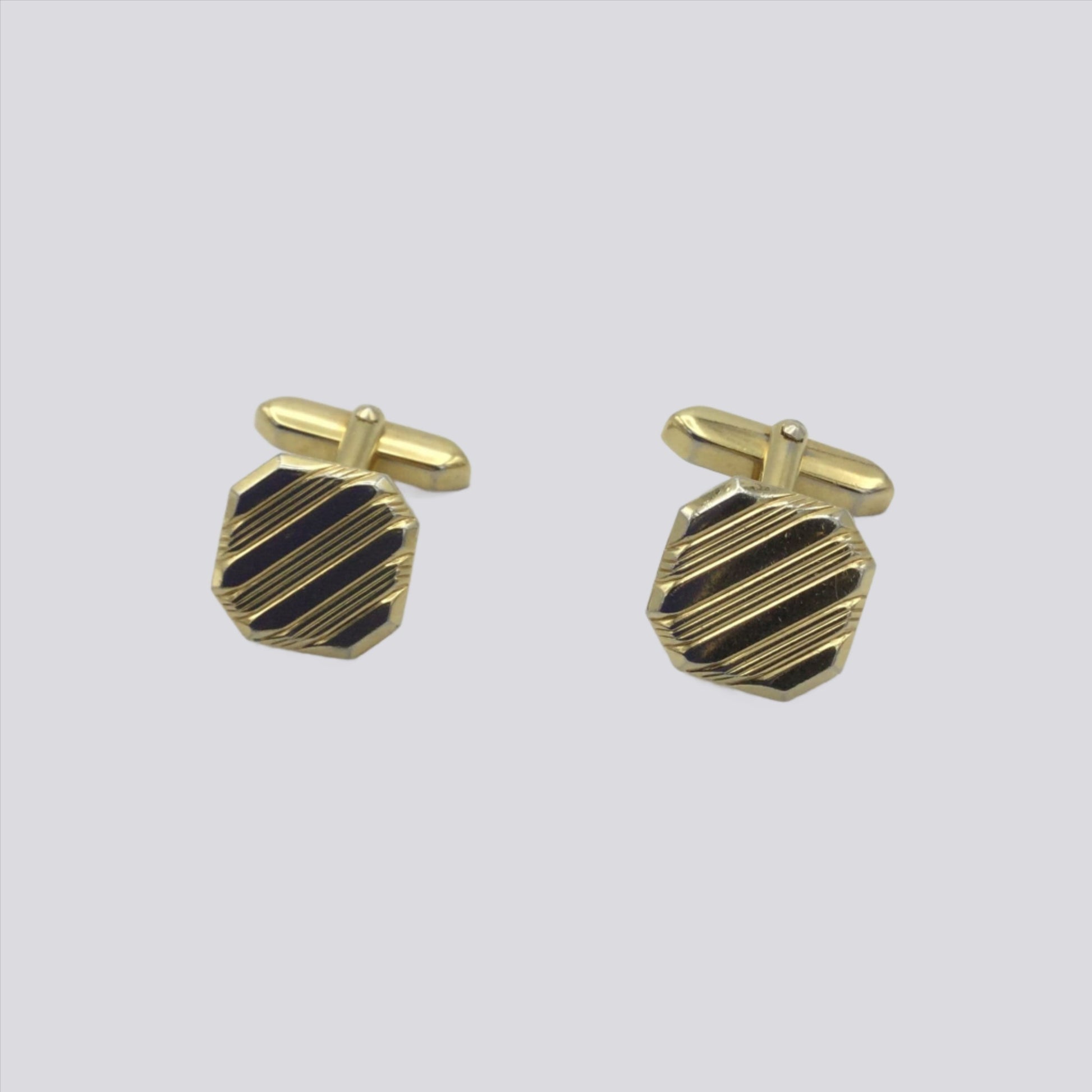 Gilded square cufflinks with a striped pattern on a white background