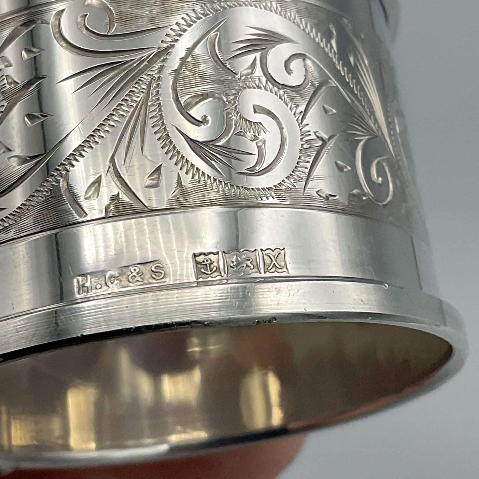 Silver hallmarks on napkin ring showing the maker's marks and Birmingham hallmark letters.