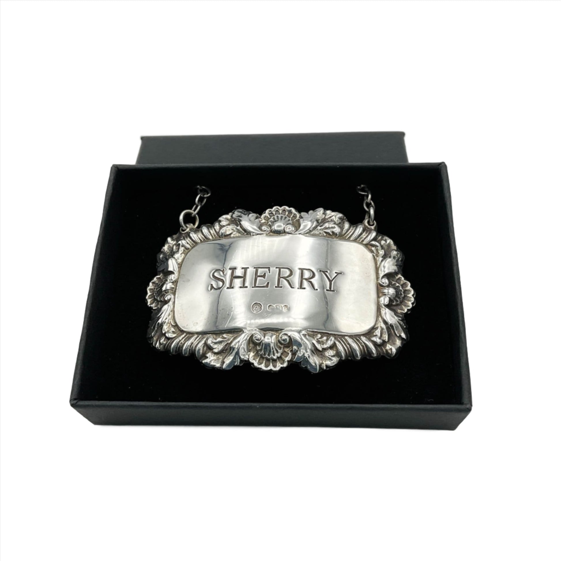 Ornate silver decanter label with Sherry engraved in the centre. The label is in a black box