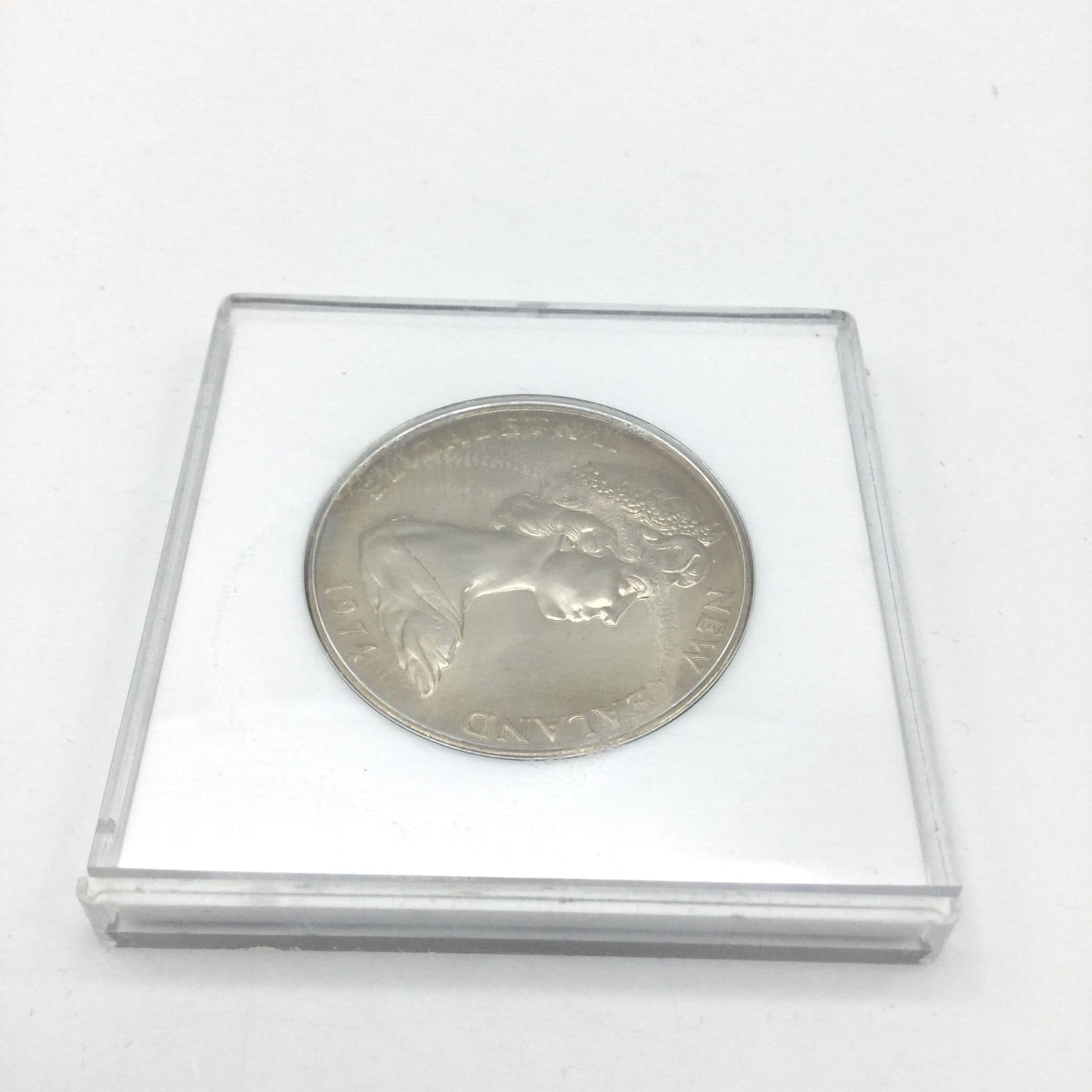 Reverse view of One dollar coin in a white case.