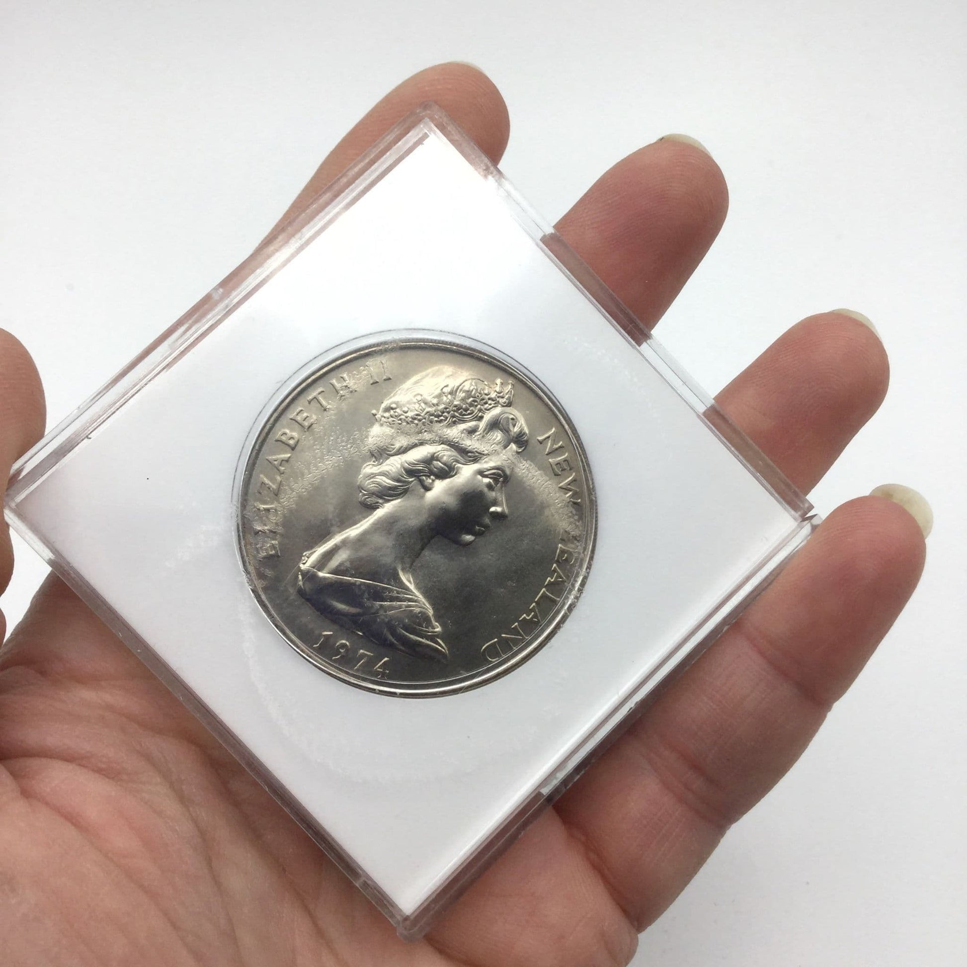 One dollar coin in a white case held in a hand