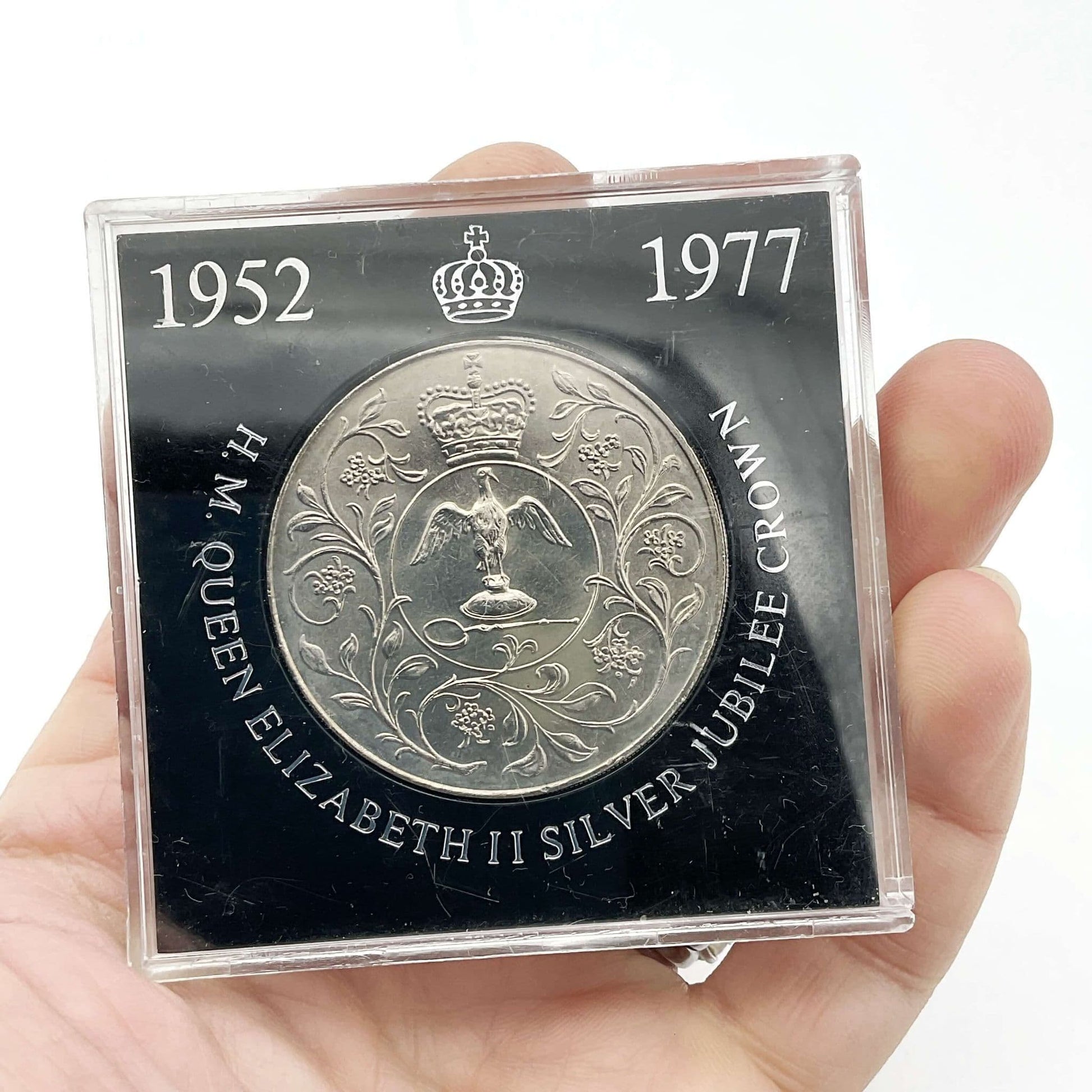 silver crown coin in a black case with HM Queen Elizabeth II Jubliee Crown held in a hand