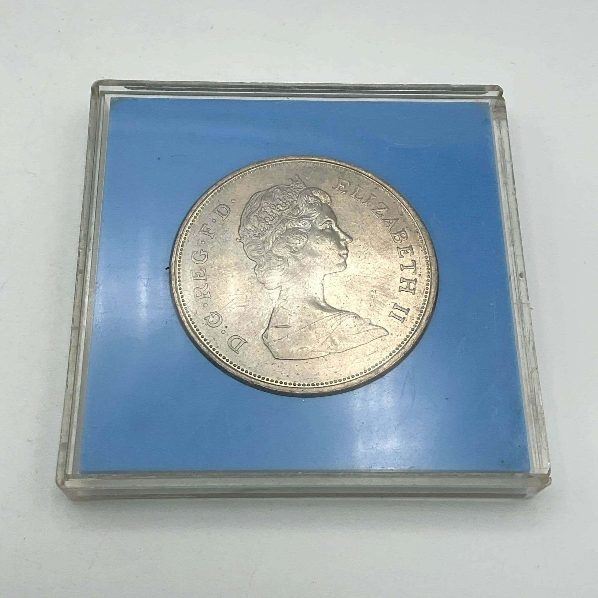 Reverse side of Silver coin featuring the Queen Mother's head in a light blue case