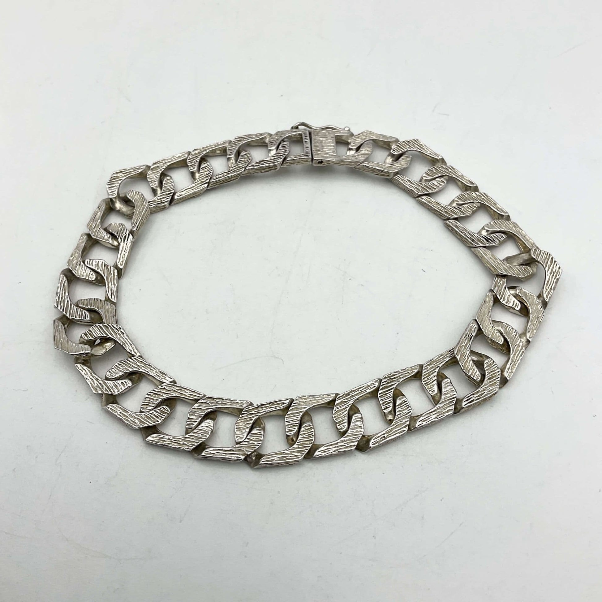 silver chain bracelet lying flat on a white background