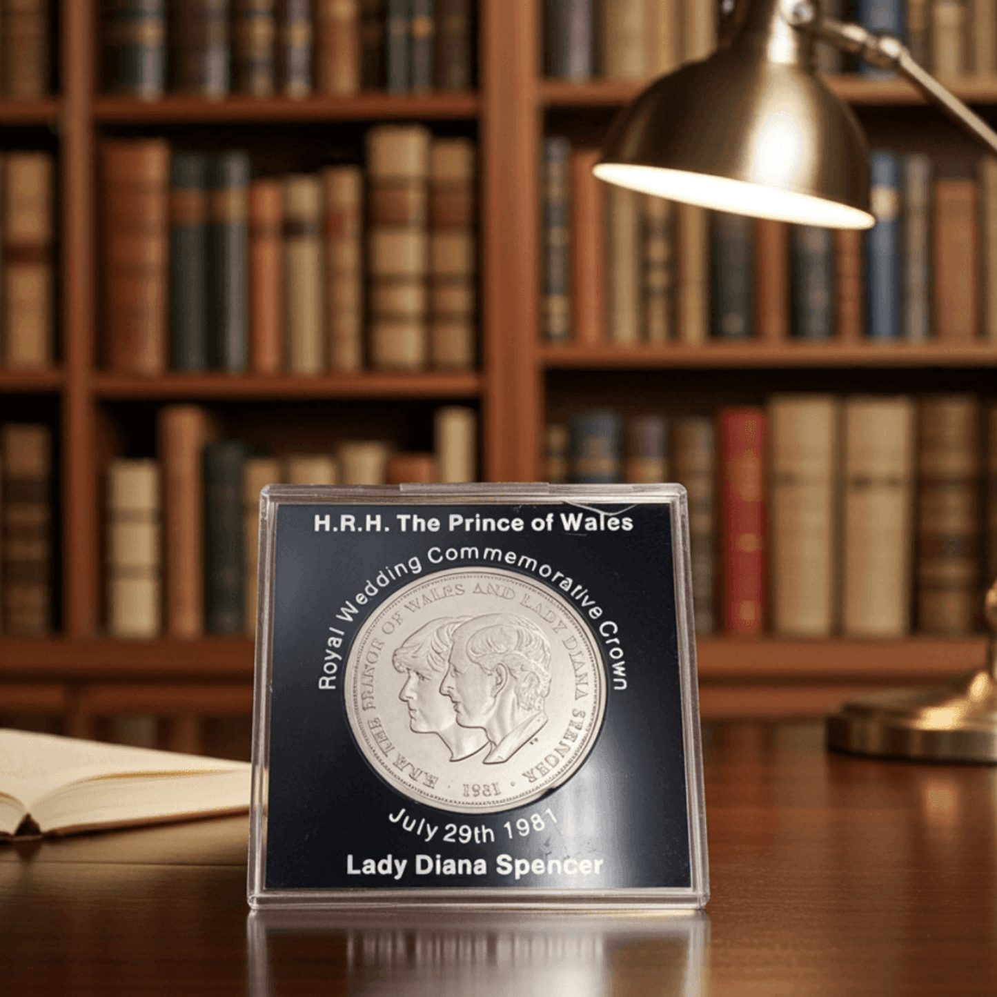 Royal wedding commemorative coin in a display case on a wooden table with bookshelves in the background