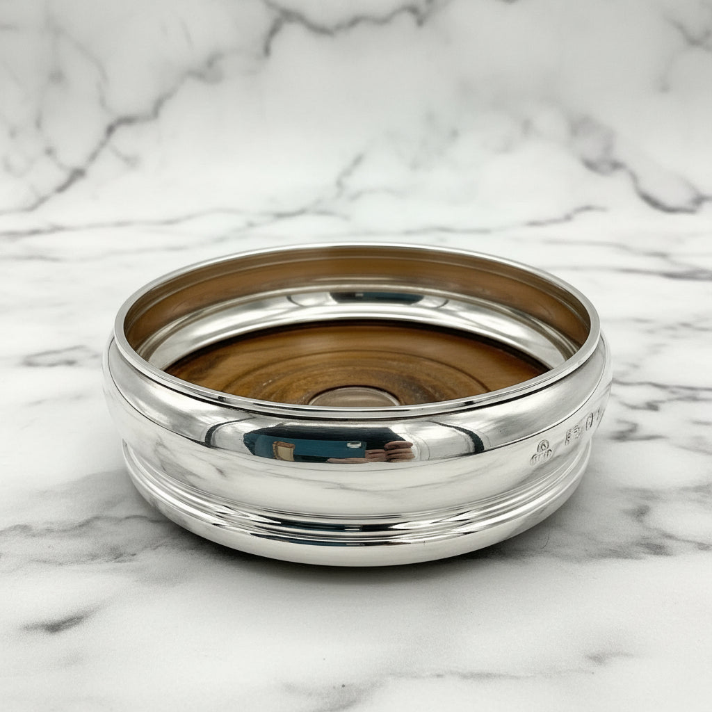 Silver bottle coaster with wooden interior on a marble surface