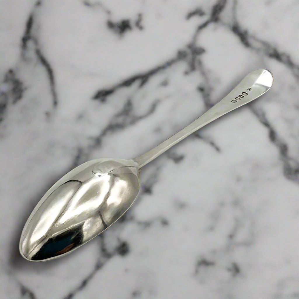back of antique silver serving spoon on a marble surface
