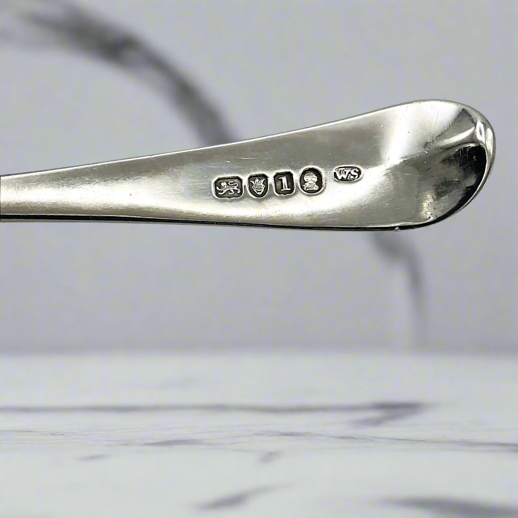 Hallmarks on a spoon handle with a marble worktop in the background
