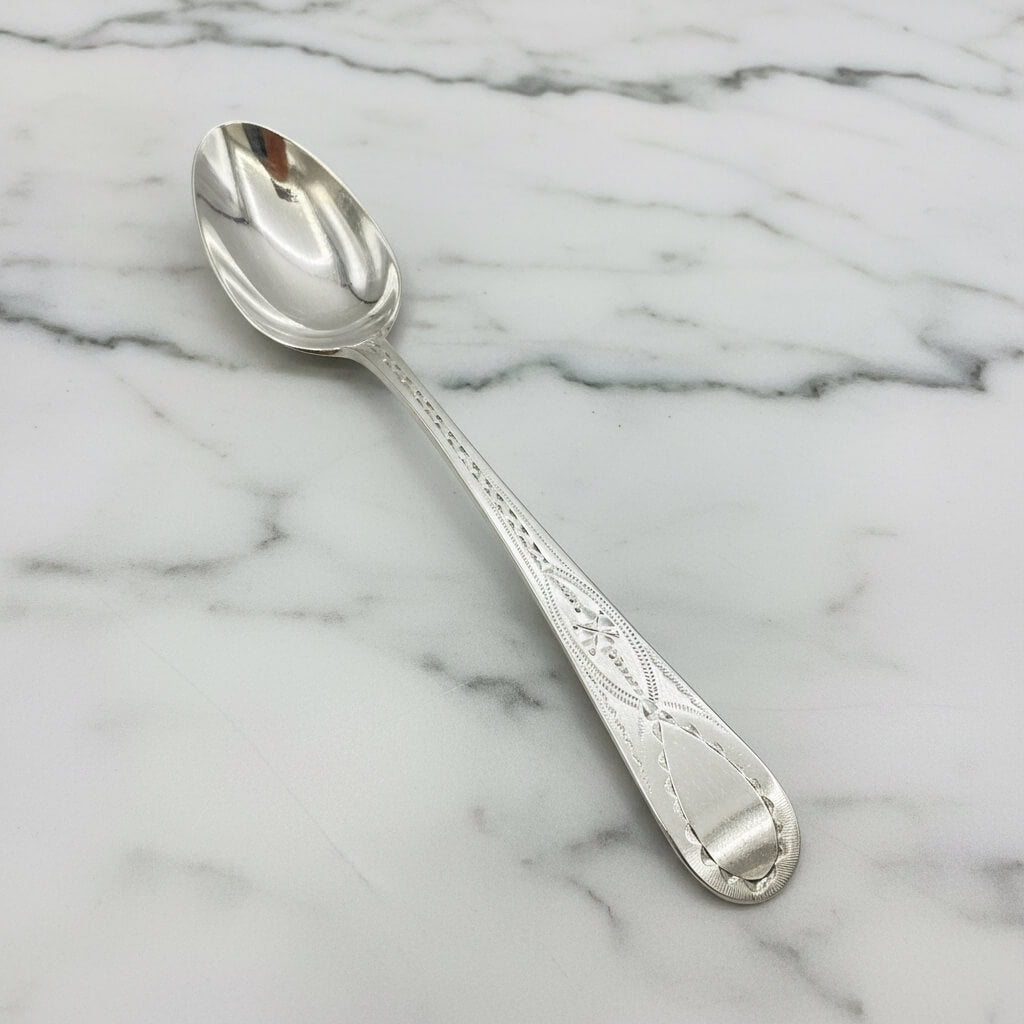 Silver spoon with engravings on a marble surface