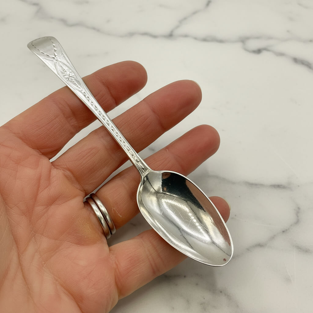 Silver spoon held in a hand against a marble background