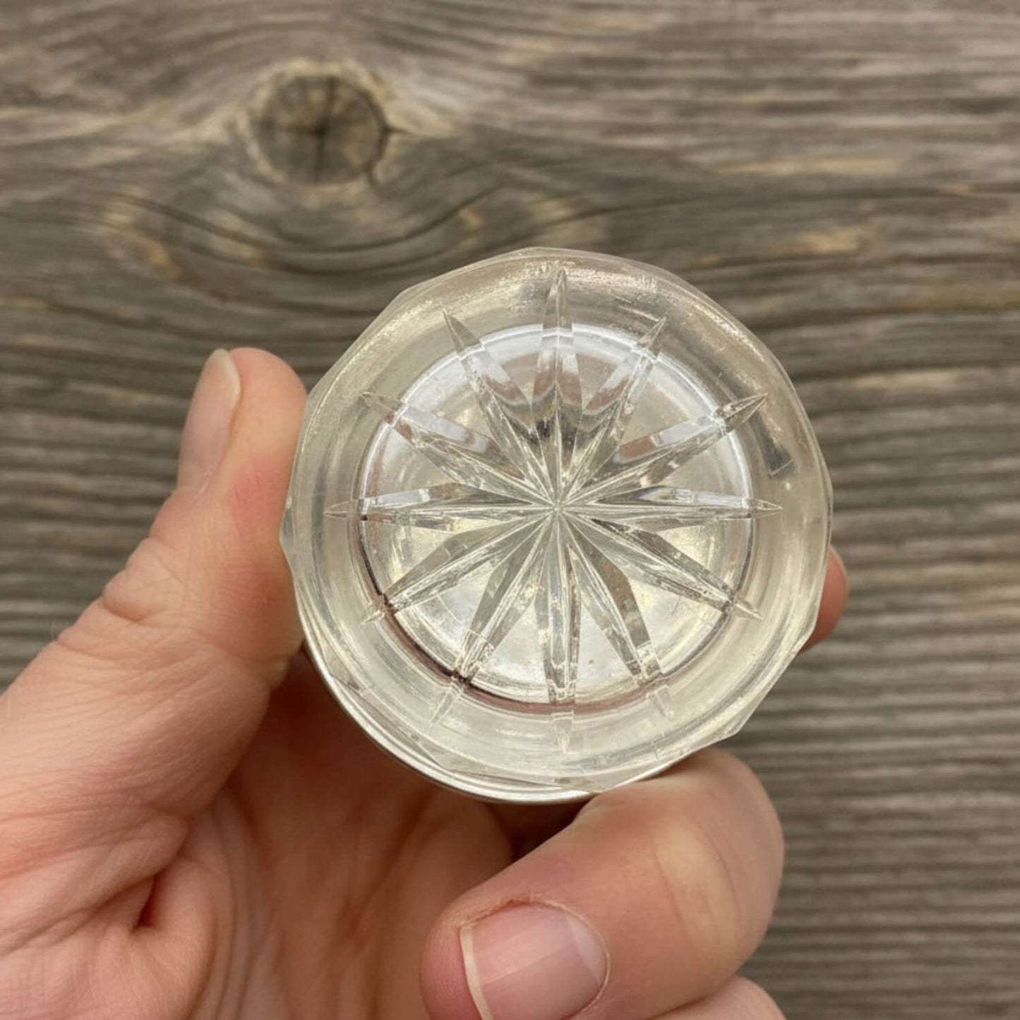 Clear crystal jar with star design held in a hand against a wooden background
