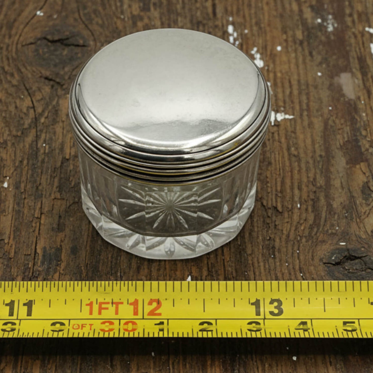 Antique 1800s Silver Lidded Vanity Jar next to a tape measure for scale on a wood surface
