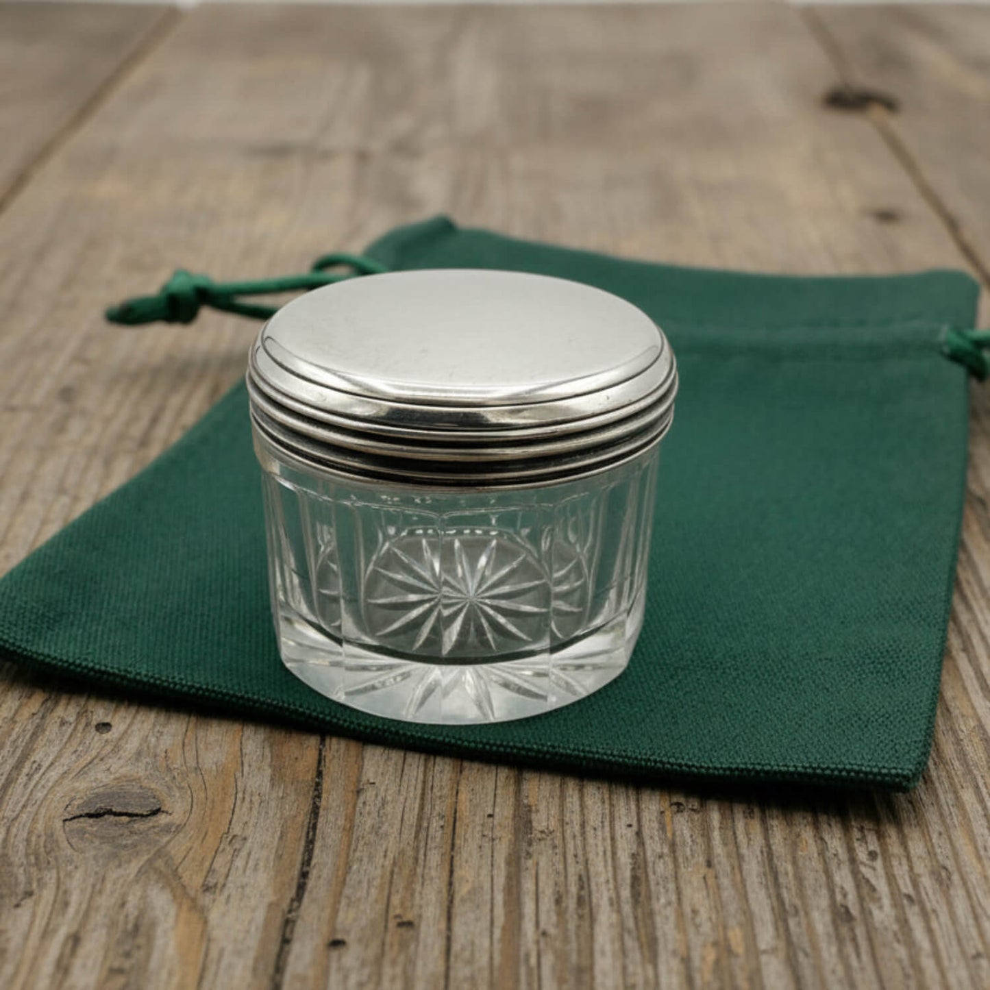 Glass jar with silver lid on a green cloth bag over a wooden surface