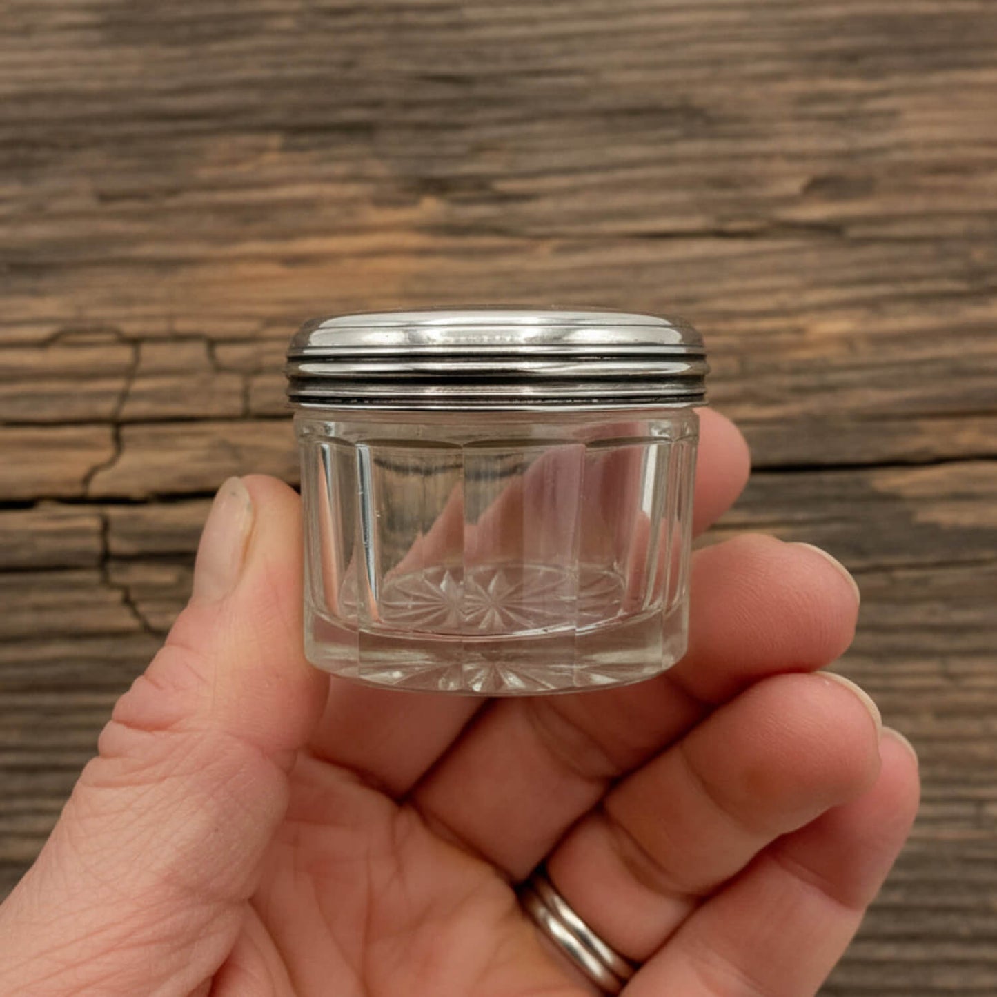 Antique 1800s Silver Lidded Vanity Jar held in a hand with a wood table in the background